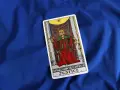 Karta XI Sprawiedliwość z talii tarot na niebieskim tle. Królowa z mieczem i wagą symbolizuje równowagę i prawdę.