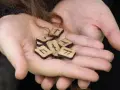 Dłonie trzymają drewniane kostki z wyrytymi symbolami. To są runy, starożytny alfabet, który kiedyś służył do pisania i wróżenia.