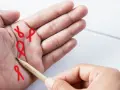 Czerwone wstążki symbolizujące nadzieję, rysowane ołówkiem na dłoni. To szczęśliwe znaki na dłoni, które niosą przesłanie.