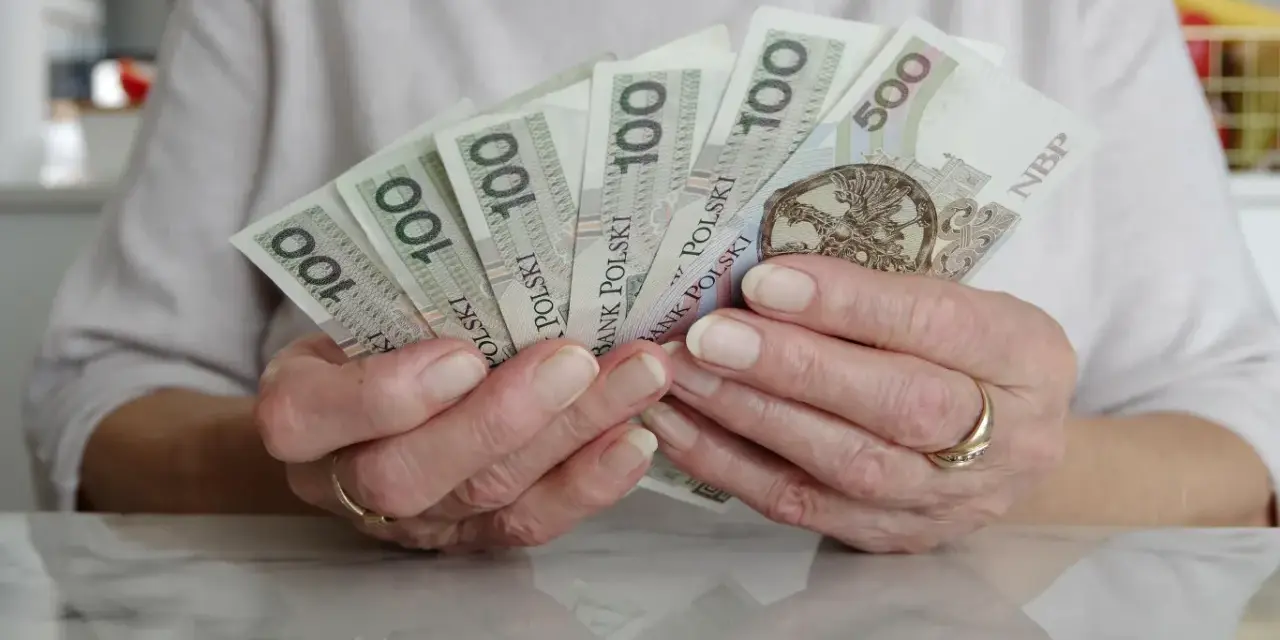 Dłonie trzymające polskie banknoty 100 i 500 zł. Numerologia 8 z dnia urodzenia może symbolizować stabilność finansową.