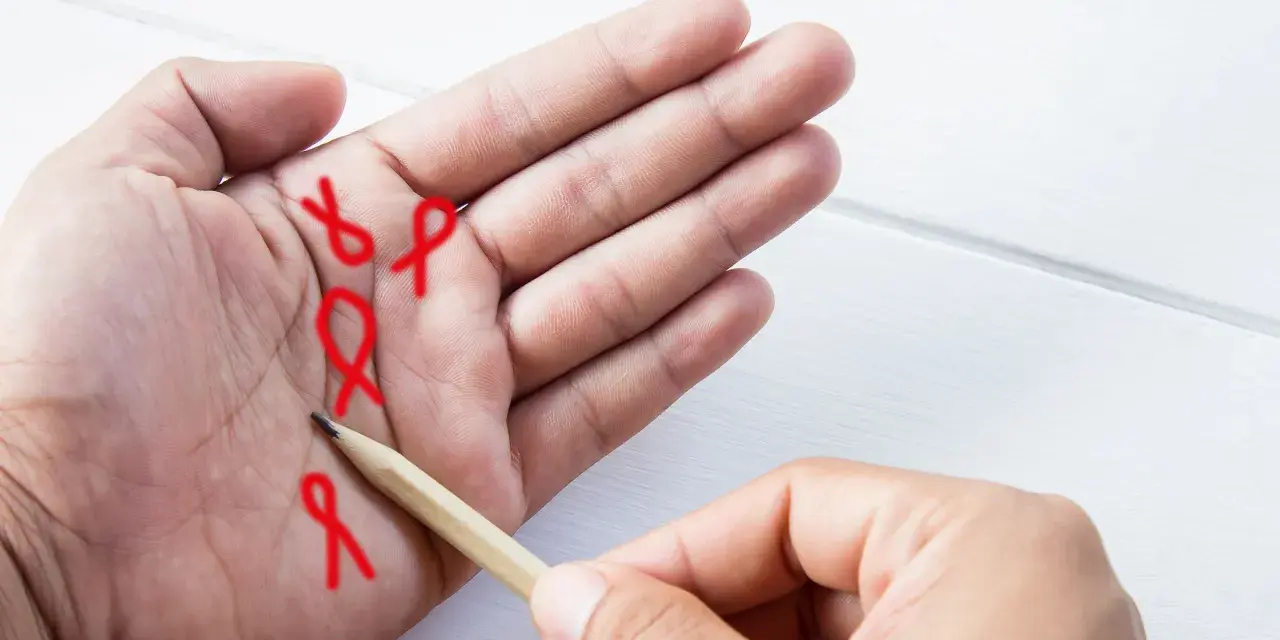 Czerwone wstążki symbolizujące nadzieję, rysowane ołówkiem na dłoni. To szczęśliwe znaki na dłoni, które niosą przesłanie.