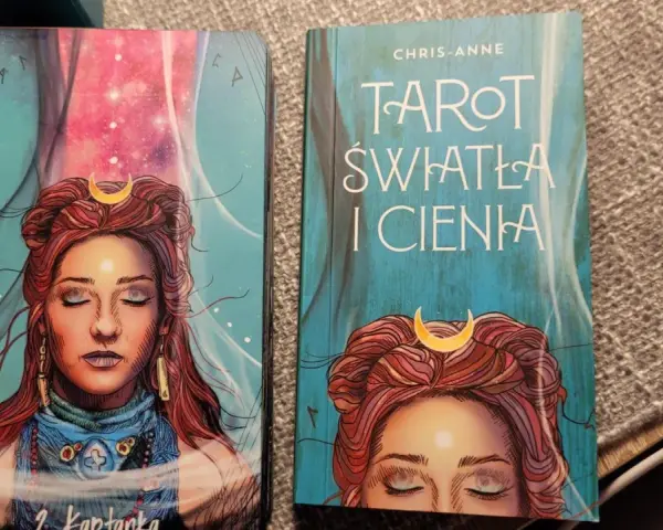 Karty i książka "Tarot Światła i Cienia" z wizerunkiem kobiety z księżycem na czole.