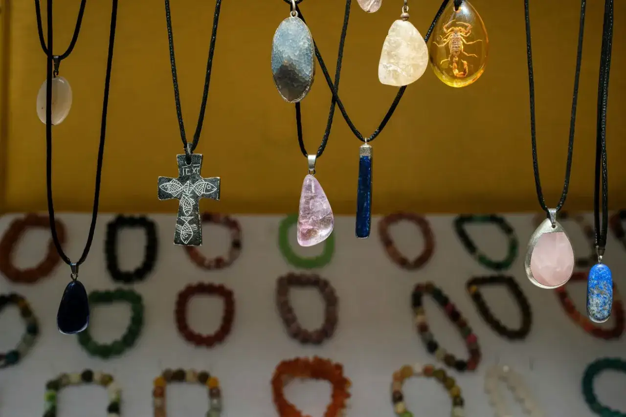 Różnorodne amulety i talizmany znaczenie: krzyż, kamienie, bursztyn ze skorpionem, wiszące na sznurkach.