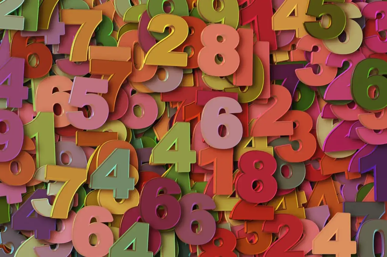 Kolorowe cyfry tworzą tło. Wśród nich wyróżnia się duża, różowa szóstka, symbolizująca 5 rok numerologiczny.